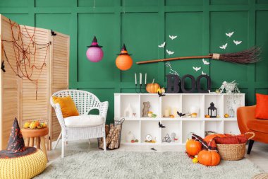 Cadılar Bayramı için dekore edilmiş oturma odasının içinde koltuk ve raf ünitesi var.