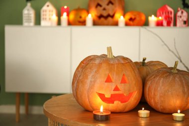 Oturma odasında yanan mumlarla Cadılar Bayramı balkabakları, yakın plan.