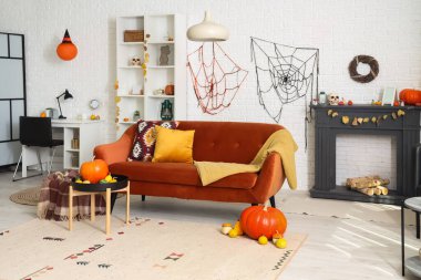 Cadılar Bayramı için kanepe ve balkabaklarıyla dekore edilmiş aydınlık oturma odasının içi.