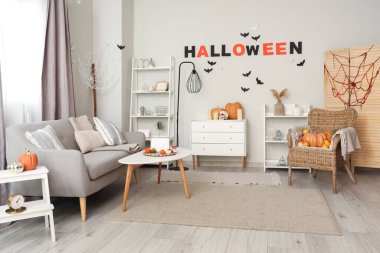 Cadılar Bayramı için dekore edilmiş oturma odasının içi kanepe ve koltukla dolu.