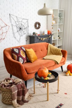 Cadılar Bayramı için kanepe ve balkabaklarıyla dekore edilmiş aydınlık oturma odasının içi.