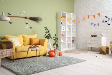 Cadılar Bayramı için sarı kanepe ve raf ünitesiyle dekore edilmiş oturma odasının içi.