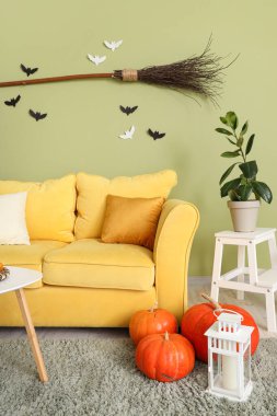 Cadılar Bayramı için sarı kanepe ve cadı süpürgesiyle dekore edilmiş oturma odasının içi.