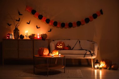 Cadılar Bayramı balkabakları ve yanan mumlarla dolu karanlık oturma odasının içinde.