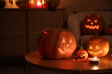 Cadılar Bayramı şekerli balkabakları ve karanlık oturma odasındaki masada yanan mumlar.