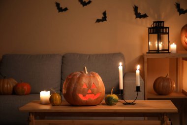 Cadılar Bayramı balkabakları ve karanlık oturma odasında yanan mumlar.