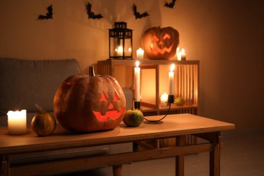 Cadılar Bayramı balkabakları ve karanlık oturma odasında yanan mumlar.