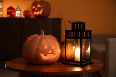 Karanlık oturma odasındaki masada yanan mumlarla Cadılar Bayramı balkabakları