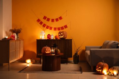 Cadılar Bayramı balkabakları ve yanan mumlarla dolu karanlık oturma odasının içinde.