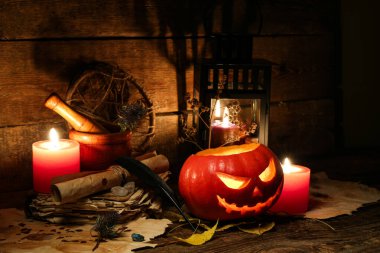 Cadılar Bayramı kompozisyonu kriko-fener, yanan mumlar, eski parşömenler ve ahşap masa yaprakları