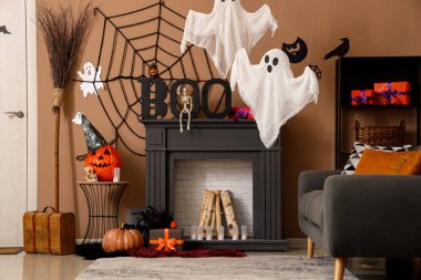 Cadılar Bayramı süslemeleri, gri kanepesi ve şöminesi olan festival salonu.