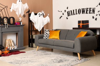 Cadılar Bayramı süslemeleri, gri kanepesi ve şöminesi olan festival salonu.