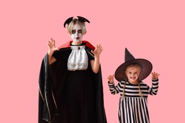 Cadılar Bayramı için giyinmiş küçük çocuklar pembe arka planda