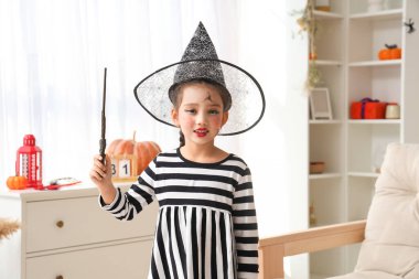 Sihirli değnekli küçük kız Cadılar Bayramı 'nı evde kutluyor.