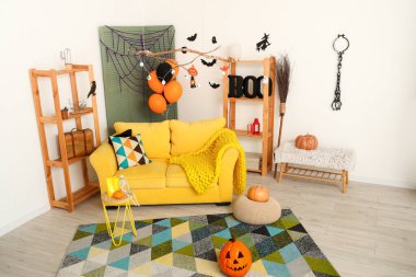 Cadılar Bayramı için dekore edilmiş oturma odasının içi kanepe ve raf üniteleriyle dolu.