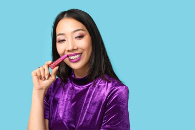 Mavi arka planda ruj izi olan güzel bir Asyalı kadın.