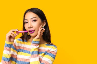 Sarı arka planda ruj izi olan güzel Asyalı kadın.