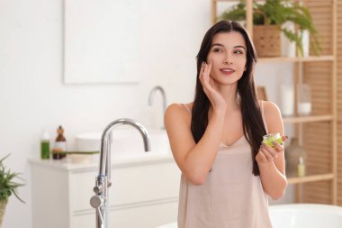 Banyoda bir kavanoz aloe vera jeli güzel, genç ve mutlu bir kadın.