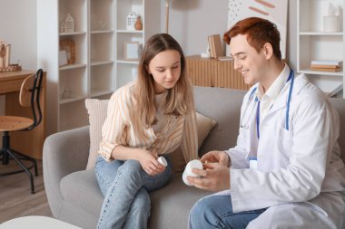 Erkek doktor, evdeki genç bayana ilaç yazıyor.