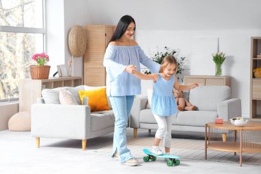 Küçük kızı evde kayarken mutlu bir anne.