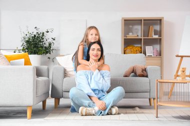 Küçük kızı evde sarılırken mutlu bir anne.