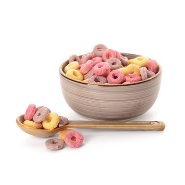 Beyaz arka planda renkli mısır gevreği halkaları olan kase ve kaşık.