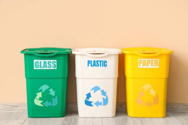 Bej duvarın yakınındaki farklı çöp kutuları için boş çöp kutuları. Geri dönüşüm kavramı