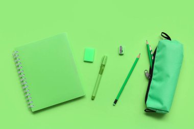 Yeşil arka planda defter ve kalem kutusu. Üst görünüm