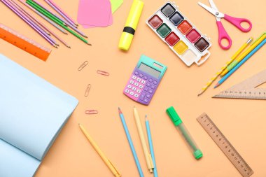 Bej arka planda hesap makinesi, suluboya ve makas. Üst görünüm