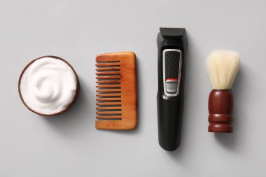 Modern budayıcı, saç fırçası ve açık gri arka planda tıraş kremi.