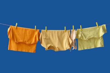 Temiz giysiler mavi arka planda ipte asılı.