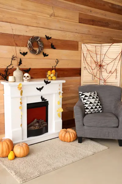 Cadılar Bayramı için dekore edilmiş oturma odasının içinde şömine ve koltuk var.