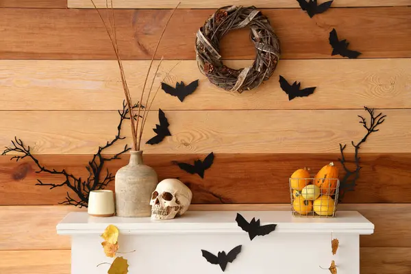 Ağaç dalları, kafatası, kağıt yarasalar ve şöminede Cadılar Bayramı balkabakları olan vazolar.