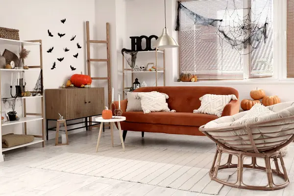 Cadılar Bayramı için dekore edilmiş oturma odasının içinde kırmızı kanepe ve koltuk var.