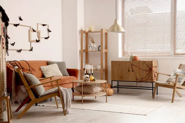 Cadılar Bayramı için dekore edilmiş oturma odasının içinde kırmızı kanepe ve koltuklar var.