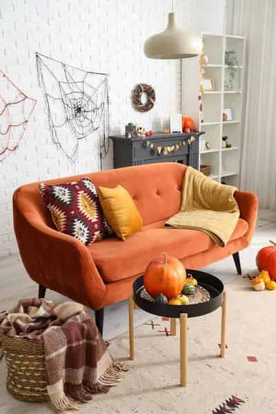 Cadılar Bayramı için kanepe ve balkabaklarıyla dekore edilmiş aydınlık oturma odasının içi.