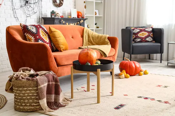 Cadılar Bayramı için kanepe ve balkabaklarıyla dekore edilmiş aydınlık oturma odasının içi.