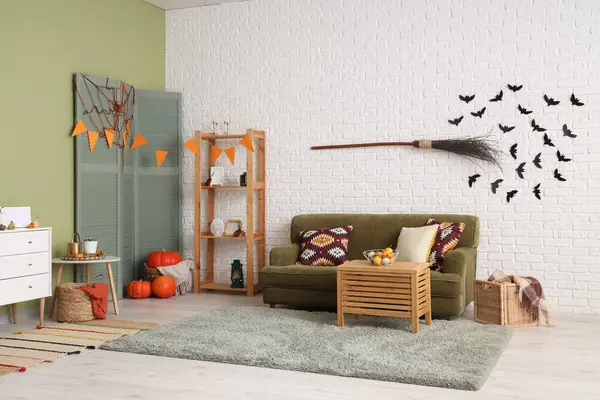 Cadılar Bayramı için yeşil kanepe ve cadı süpürgesiyle dekore edilmiş oturma odasının içi.