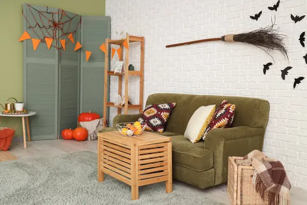 Cadılar Bayramı için yeşil kanepe ve cadı süpürgesiyle dekore edilmiş oturma odasının içi.
