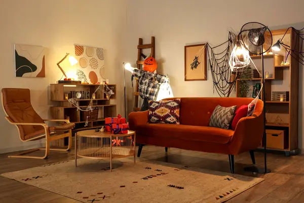 Cadılar Bayramı süslemeleri, parlak lambaları, kahverengi kanepesi ve kahve masası olan festival salonu.