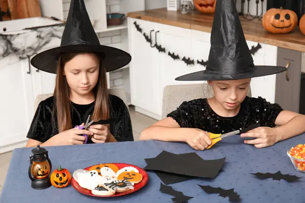 Cadılar Bayramı için giyinmiş şirin kızlar mutfakta yarasa kesen cadılar gibi.