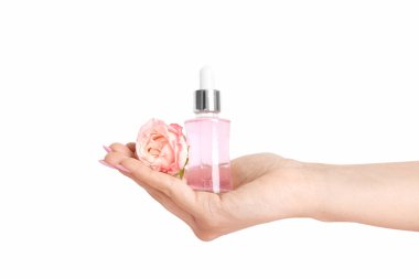 Kozmetik yağlı kadın eli ve bej arka planda gül.