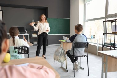 Olgun öğretmen sınıftaki küçük öğrencilere ders veriyor.