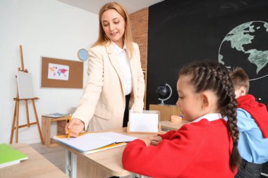 Olgun öğretmen sınıftaki küçük öğrencilere coğrafya dersi veriyor.