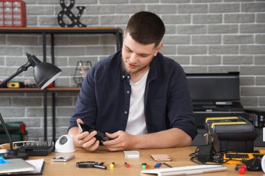 Servis merkezinde cep telefonunu tamir eden erkek teknisyen