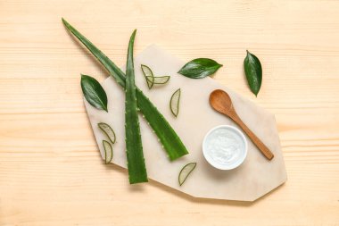 Ahşap arka planda yaprakları olan bir kase aloe vera jel ve pansiyon.