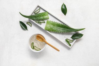 Bir kase aloe vera jeli ve beyaz arkaplanda yapraklar