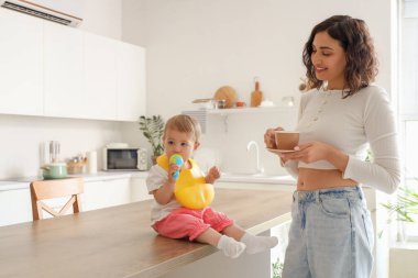Masada küçük, şirin bir bebek ve mutfakta kahve içen bir anne.