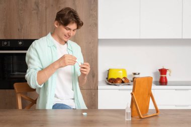 Cımbızlı genç adam mutfakta kontak lens takıyor.