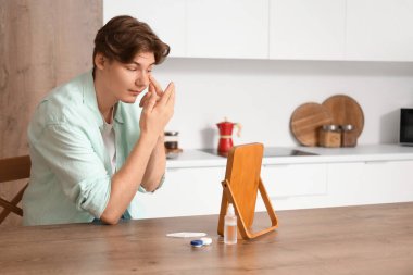 Genç adam evdeki aynanın yakınına kontak lens takıyor.